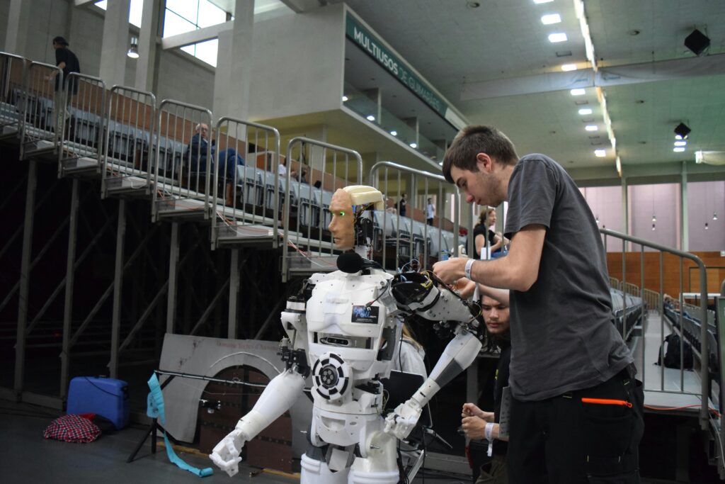 Technician working on humanoid robot at a tech exhibition in Guimaraes, Portugal.