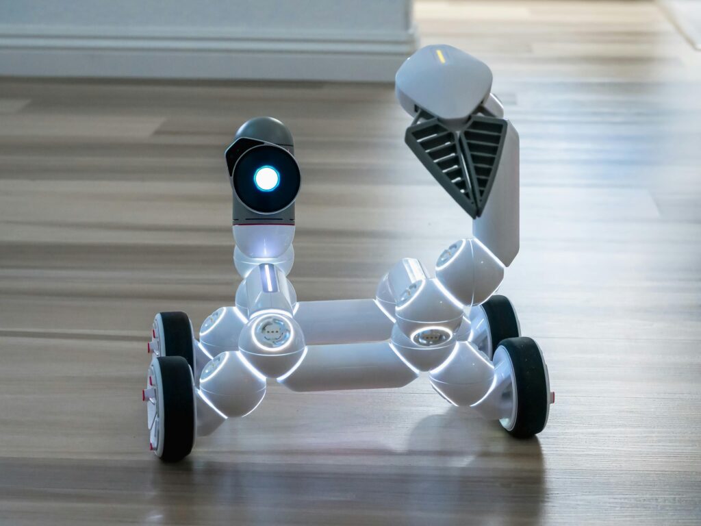 Close-up of a wheeled robot toy with a spotlight in an indoor setting, showcasing modern technology.