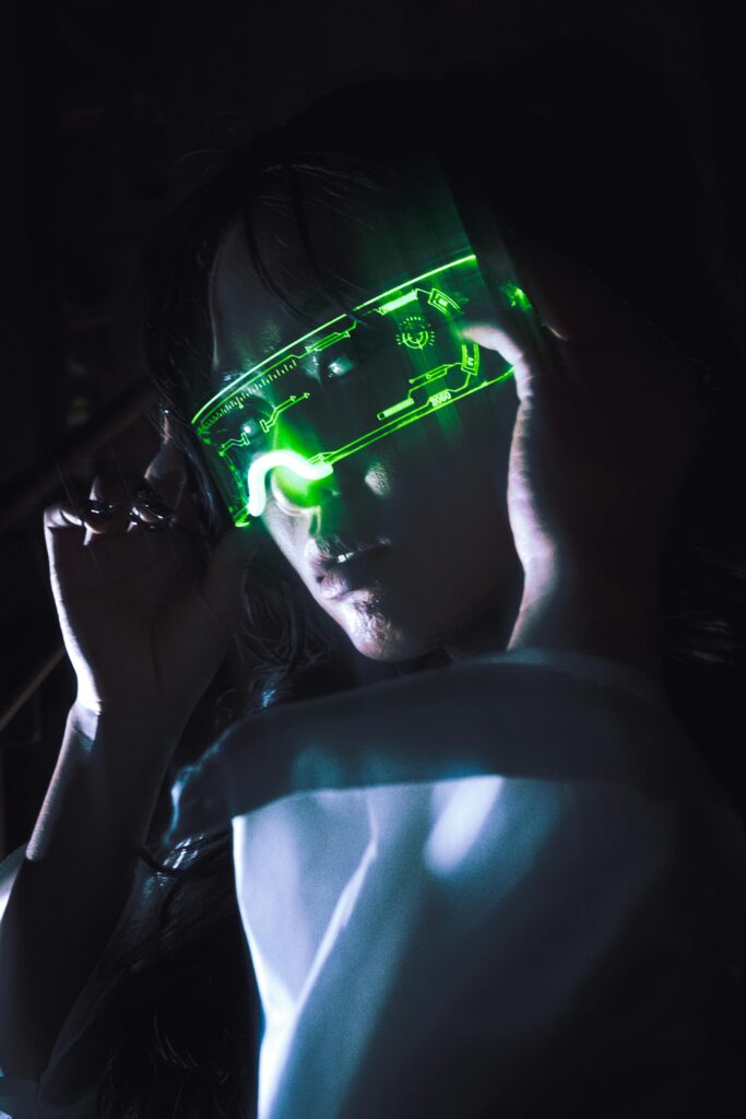 A woman wearing illuminated green neon glasses, creating a dark futuristic cyberpunk vibe.